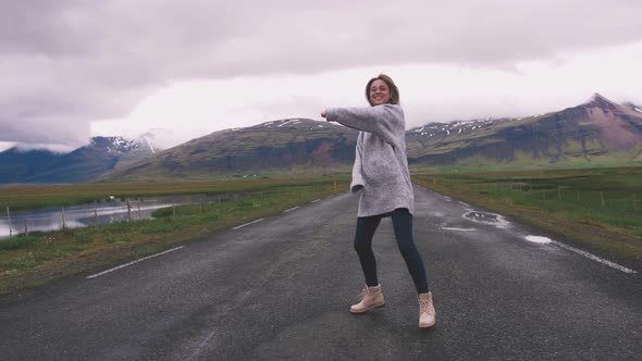 Happy Young Woman Dancing on Asphalt Road in Iceland and Having Some Fun Slow Motion