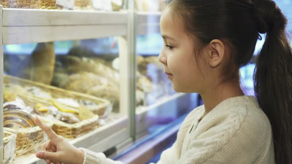 Close Up Shot of a Pretty Little Girl Posinting at the Desserts at the Bakery