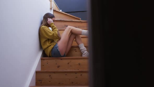 Woman using smartphone while sitting on stairs at home