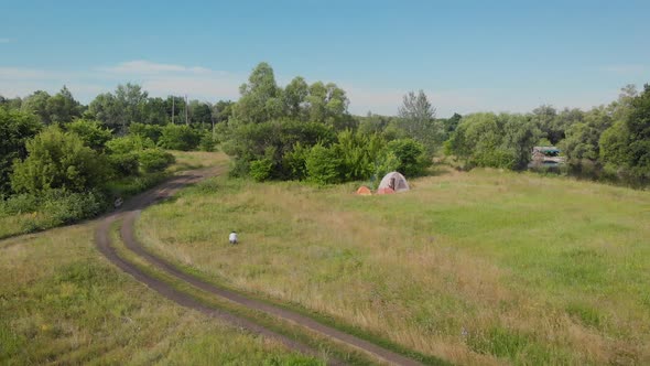 A Small Camp in the Fields. Tourists Stopped in a Beautiful Natural Place with Three Tents, Cook