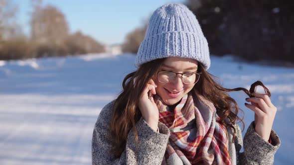 Young Woman Standing on the Winter Road She is Talking on Phone at Sunny Day