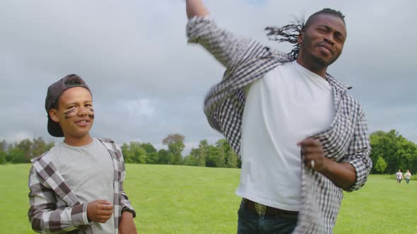 Cute Black Son with Dad Learning to Pitch Baseball Outdoors