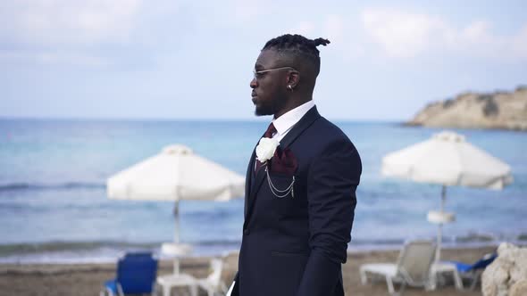 Portrait of Confident African American Groom Standing on Luxurious Summer Resort Waiting for Bride