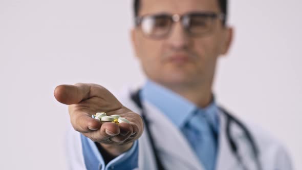 Middle Aged Male Doctor Holds Big Green Pills in Palm, Spills Them on Floor