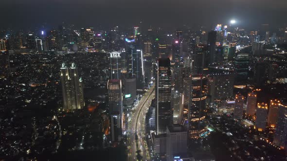 Descending Aerial Pedestal Shot of Night Time Highway Traffic Through Busy Modern City Center in