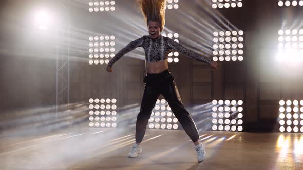 Full Body Shot of Woman Dancing and Swaying Her Hair on Sage Against Spotlight