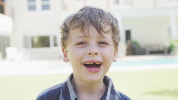 Portrait of smiling caucasian boy looking at camera by pool