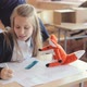 The girl sits at the desk in the classroom and draws - VideoHive Item for Sale
