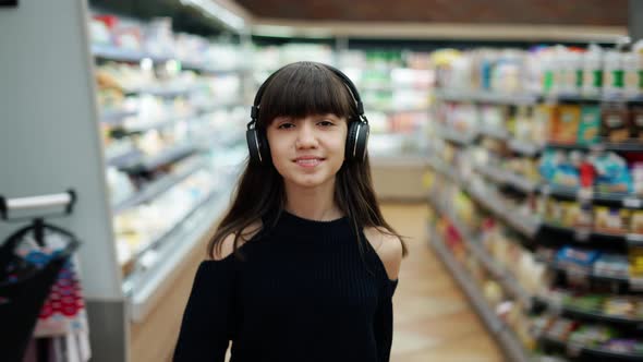 Smiling Teenager Walking in the Supermarket in Headphones