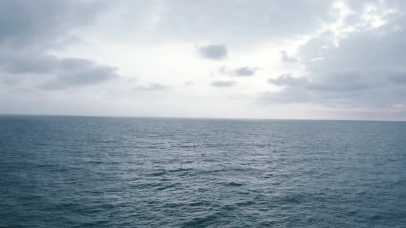 Aerial view flying over the ocean towards the horizon