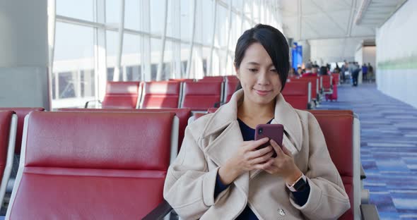 Businesswoman check on the cellphone and wait for the flight in the airport