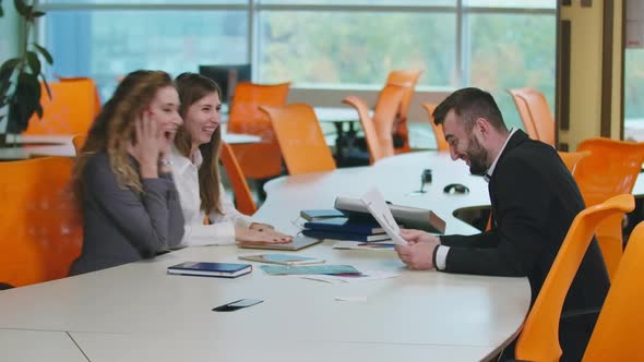 Excited Women Gesturing Success Smiling Sitting with Man at Table in Office