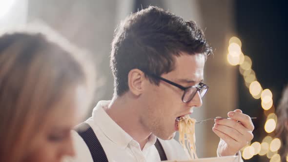 Close Up Portrait of Young Hipster Guy Eating at Table at Party or Celebration