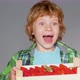 Blonde boy is happy about delicious strawberries from the farmers market. - VideoHive Item for Sale