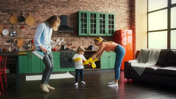 Spouses and Their Little Son in Yellow Rubber Gloves are Smiling and Dancing with Cleanser and Broom