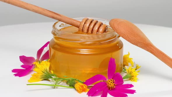 Honey Dripping Pouring From Honey Dipper In A Glass Jar Bowl