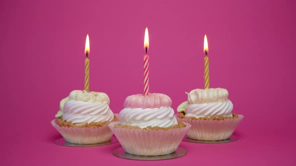 birthday cupcake with candles and birthday decorations on pink background