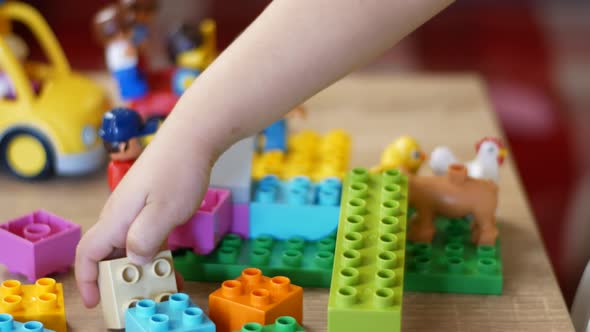 Little girl plays building blocks on a wooden table