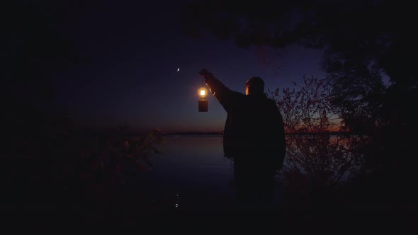 Man with a Lamp on the River Bank