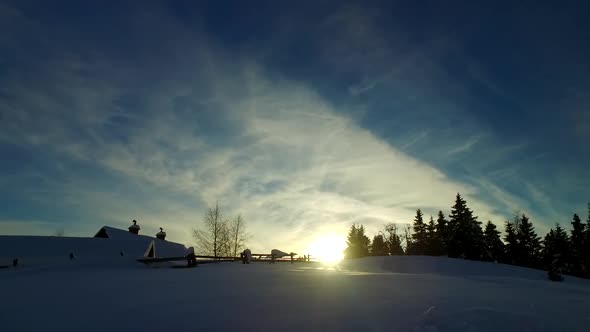 Some Cabins Near Cold Winter Forest in the Sunset