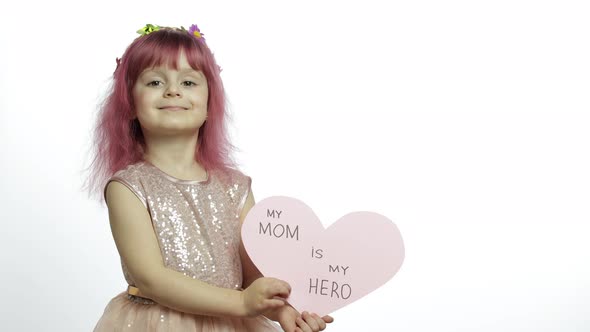 Child Girl Princess Holds Pink Paper Heart with Text About Mother. Mother's Day