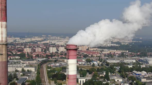 Aerial view of high chimney pipes with white smoke from power plant