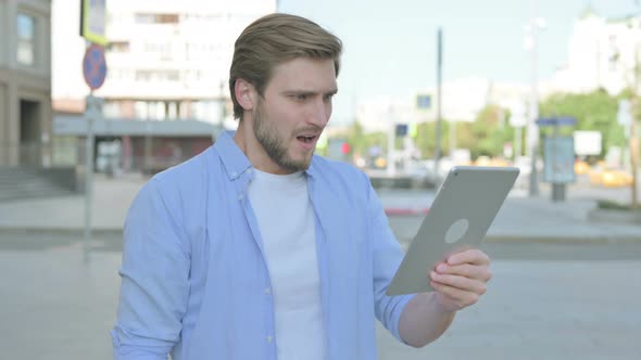 Upset Man Reacting to Loss on Tablet Outdoor