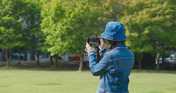 Woman use of mobile phone to take photo in countryside
