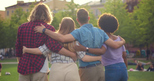 Rear View of Young Mixedrace People Hugging Standing in Summer Park