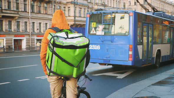Courier with Insulated Backpack on Bicycle Delivering Food in the City. Food Delivery Service