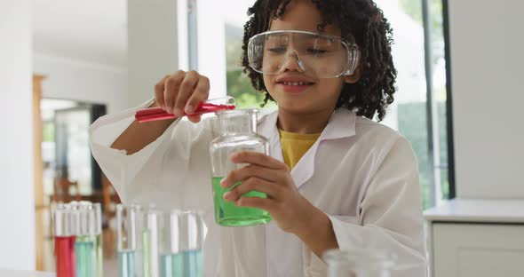 Happy biracial boy making chemistry experiments, holding test tube