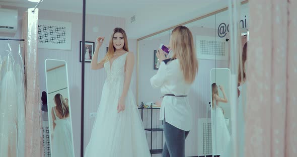 Beautiful Girl Makes the Fitting of a Luxurious Wedding Dress in Front of a Mirror