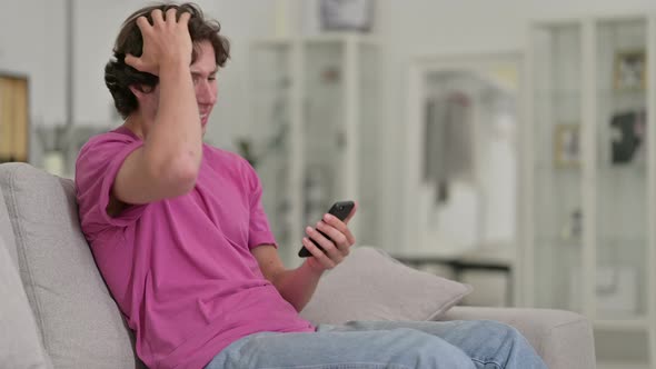 Upset Casual Young Man Having Loss on Smartphone at Home 