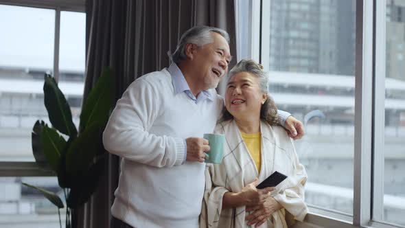 Asian  mature senior couple using tablet and spending time together in living room at home.