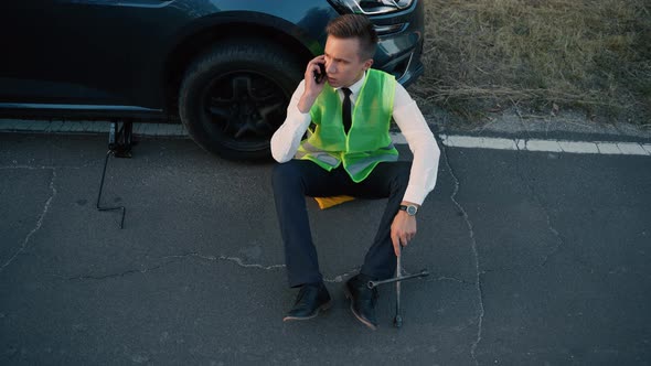 Top View of a Man in a Green Safety Vest Talking on Cell Phone