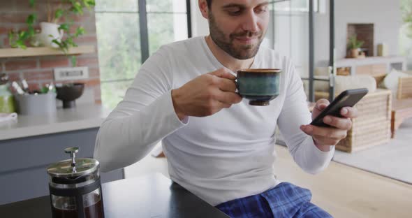 Man drinking coffee and using mobile phone at dining table in a comfortable 4k