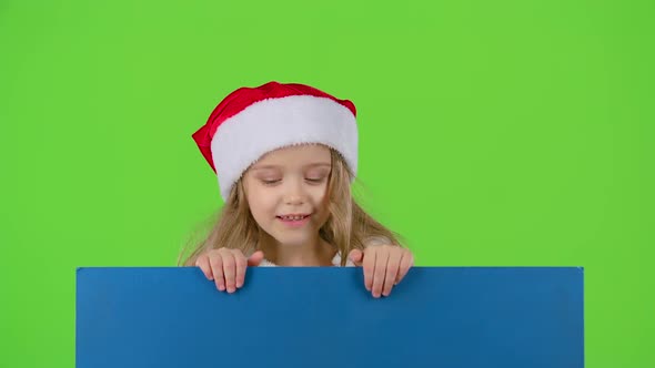 Child Girl in a New Year's Cap Jumps and Shows a Finger Down. Green Screen