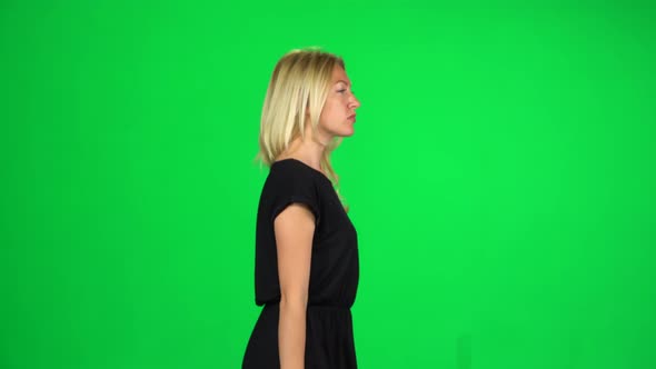 Pensive Woman Is Walking on a Green Screen at Studio. Side View