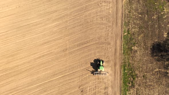 Aerial view large tractor cultivating a dry field. Top down aerial view tractor cultivating ground 