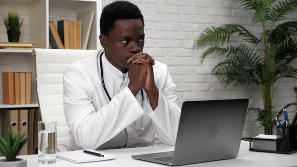 Thoughtful African American Man Doctor Thinking About Future Operation in Clinic