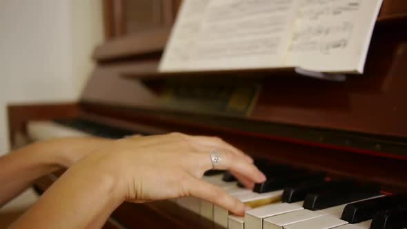 Hobby female pianist playing a melodic piece on antique vintage 100 year old piano