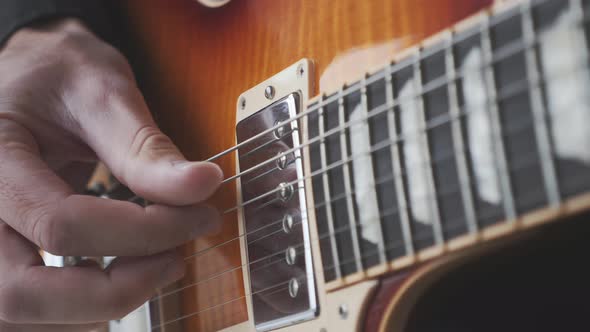 Fingerstyle guitar player practicing song on guitar. Hands picking and pulling guitar strings. 