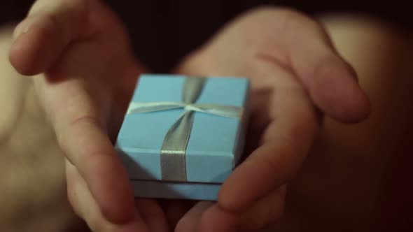 Man Holds Out a Gift in a Blue Box