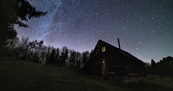 Romantic Starry Night Sky Milky Way Galaxy Rotates over Wooden Hut in Wild Forest Nature Astronomy