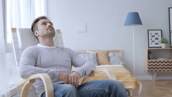 Pensive Adult Man Relaxing on Chair and Looking at Roof