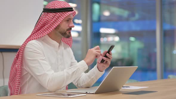 Professional Arab Businessman Using Smartphone and Laptop