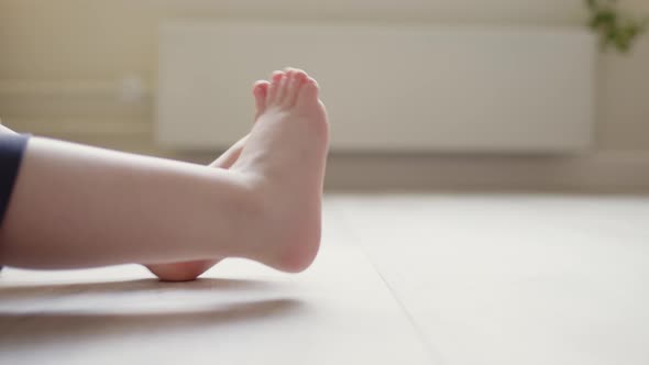 Close Up Small Children Legs in Frame on Wooden Laminate on Floor in Large Bright Room