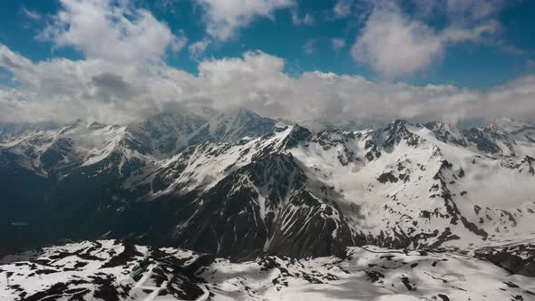 Air Flight Through Mountain Clouds Over Beautiful Snowcapped Peaks of Mountains and Glaciers