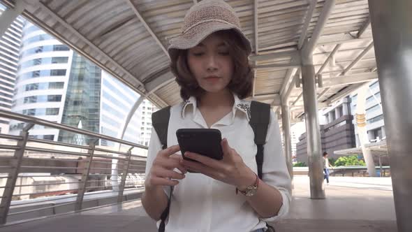 Asian backpacker blogger woman using smartphone for direction and looking on location map