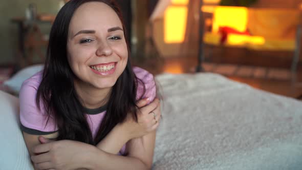 Pretty Young Woman in Pajamas Resting on Bed in Morning. Portrait of Charming Female Looking at